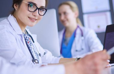 Ciddi bir tıbbi ekip parlak bir ofiste dizüstü bilgisayar kullanıyor.