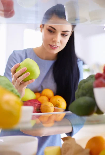 Smiling woman taking a fresh fruit out of the fridge, healthy food concept — Stock Photo, Image