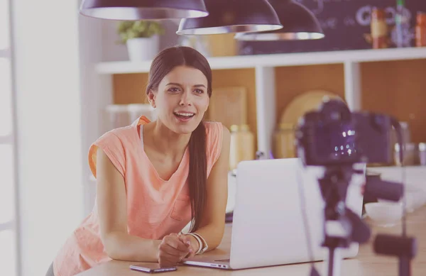 Ung kvinna i köket med bärbar dator ser recept, leende. Begreppet livsmedelsbloggare — Stockfoto