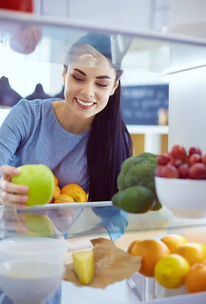 Mosolygó nő vesz egy friss gyümölcsöt ki a hűtőből, egészséges étel koncepció — Stock Fotó