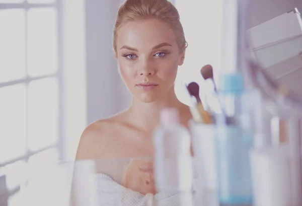 Young woman in bathrobe looking in bathroom mirror — Stock Photo, Image