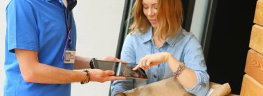 Mavi üniformalı gülümseyen kurye servis konseptine paket kutusu teslim eden teslimatçı. Mavi üniformalı gülümseyen teslimatçı.