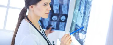 Stetoskop lu genç gülümseyen kadın doktor doktor ofisinde röntgeni işaret ediyor