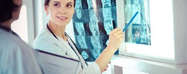 İki gülümseyen doktor hastane muayene odasında röntgenleri gösteriyor.