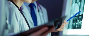 Bir grup doktor bir klinikte röntgenleri inceliyor, teşhis koymayı düşünüyorlar.