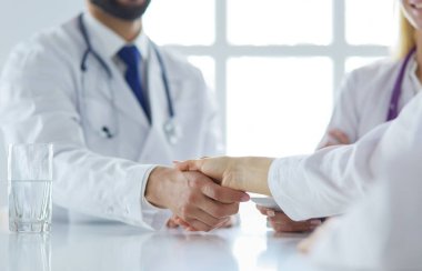 Doktor ofiste erkek bir hastayla el sıkışıyor.