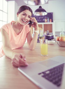 Mutfakta dizüstü bilgisayara benzeyen tariflerle gülümseyen genç bir kadın. Gıda blogcusu kavramı