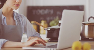 mutlu bir kadın mutfakta o onu laptop haber okuma