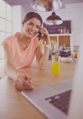 Mutfakta dizüstü bilgisayara benzeyen tariflerle gülümseyen genç bir kadın. Gıda blogcusu kavramı