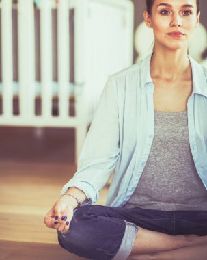 Genç kadın lotus pozisyonunda evde Yoga yapıyor. Genç kadın yoga yaparken.