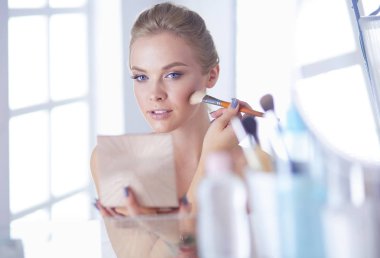 Genç bir kadının banyoya yüz pudrası sürerken fotoğrafı.