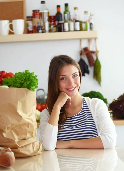 Eine junge Frau mit einer Einkaufstasche mit Gemüse in der Hand steht in der Küche. junge Frau — Stockfoto
