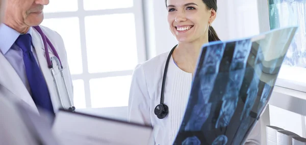 Χαμογελώντας γιατροί συζητούν τη διάγνωση των ασθενών κοιτάζοντας ακτινογραφίες σε ένα νοσοκομείο — Φωτογραφία Αρχείου