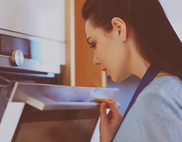 Hermosa joven comprobando cómo le va a su pastel en el horno — Foto de Stock