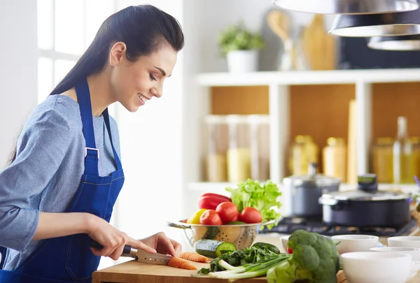 Junge Frau schneidet Gemüse in Küche zu Hause — Stockfoto