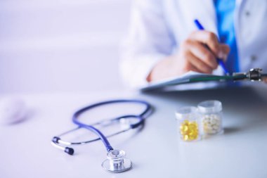 Kadınların elleri bir kağıt parçasına yazı yazıp masasında kalem bırakırlar.