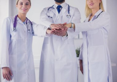 Doktorlar ve hemşireler tıbbi bir ekipte el ele tutuşuyorlar.