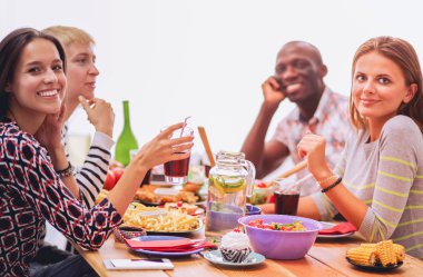 Ahşap masada otururken birlikte yemek yiyen bir grup insanın üst düzey görüntüsü. Masada yemek var. İnsanlar fast food yiyor..