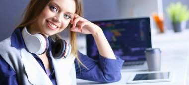 Ofis masasında çalışan ve dizüstü bilgisayarla yazan kendine güvenen genç bir iş kadını.