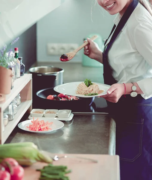 Junge Frau steht am Herd in der Küche — Stockfoto