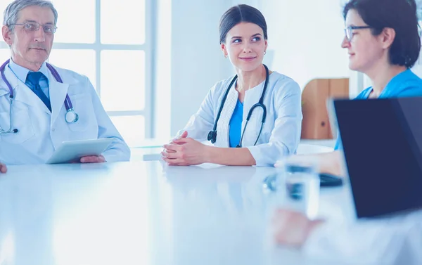 Equipo médico serio discutiendo casos de pacientes en un consultorio luminoso — Foto de Stock