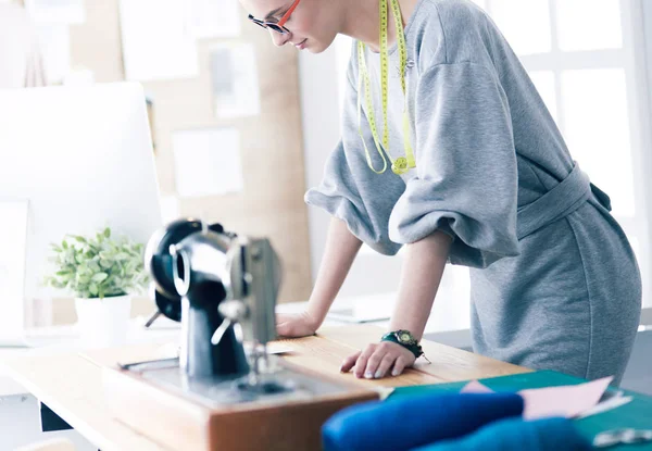 Neue modische Stile schaffen. Fröhliche junge Frau näht, während sie an ihrem Arbeitsplatz in der Modewerkstatt sitzt — Stockfoto