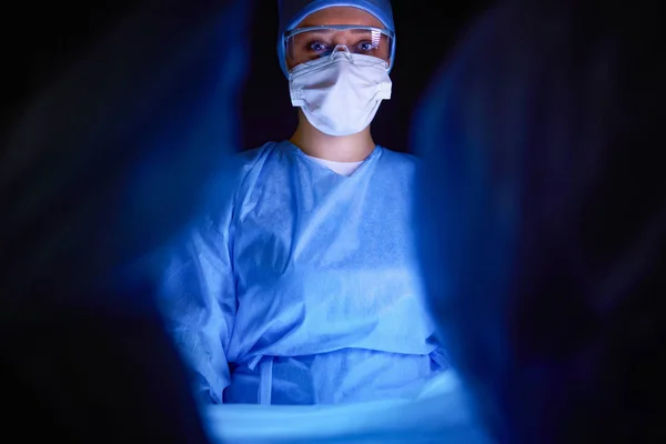 Ärzteteam in der Chirurgie vor dunklem Hintergrund. — Stockfoto