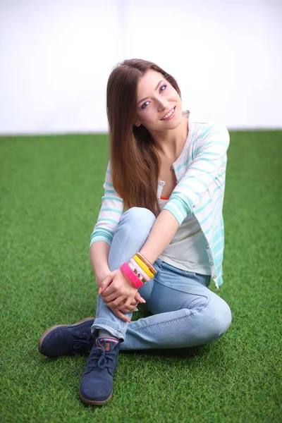 Ein schönes Mädchen sitzt auf einer Parkbank vor grünem Hintergrund — Stockfoto