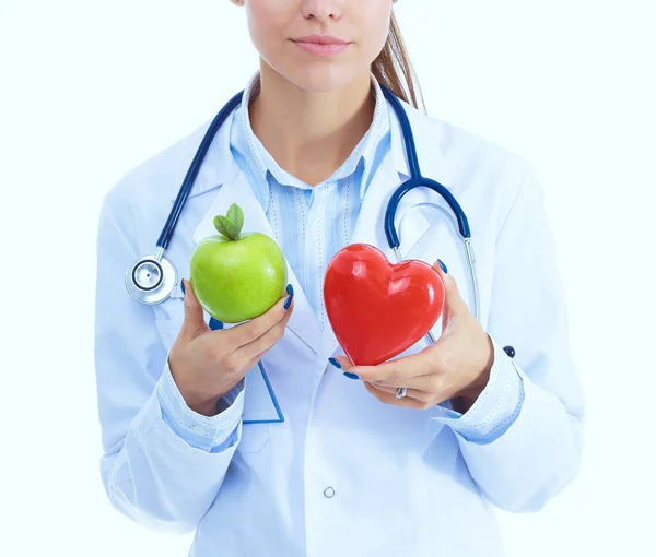 Hermosa doctora sonriente sosteniendo corazón rojo y manzana verde. Mujer doctora — Foto de Stock