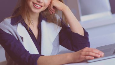 Ofis masasında çalışan ve dizüstü bilgisayarla yazan kendine güvenen genç bir iş kadını.