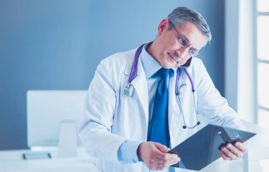 Erkek doktor hastanedeki panoya notlar yazıyor.