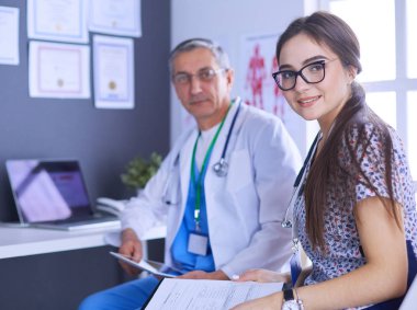 Parlak bir ofiste konuşan iki doktor.