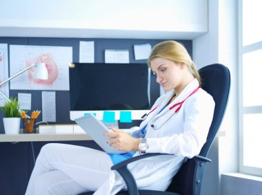 Masasında elinde dijital tabletle oturan kadın doktor.