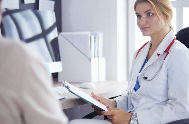 Bir doktor konuşuyor ve bir hastayı muayene ediyor.