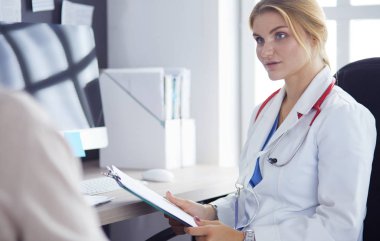 Bir doktor konuşuyor ve bir hastayı muayene ediyor.