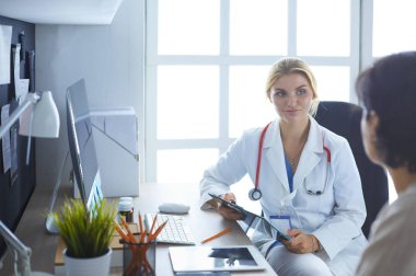 Bir doktor konuşuyor ve bir hastayı muayene ediyor.