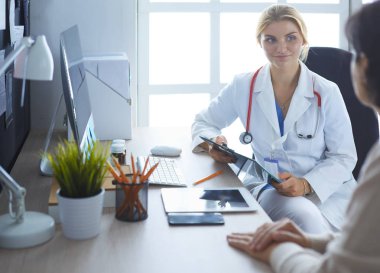 Bir doktor konuşuyor ve bir hastayı muayene ediyor.