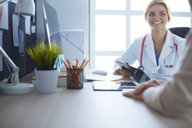 Bir doktor konuşuyor ve bir hastayı muayene ediyor.