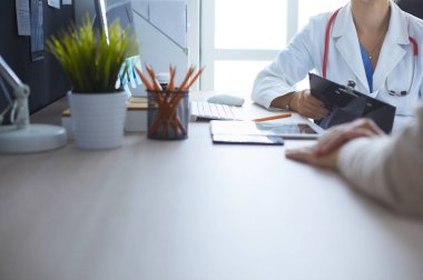Bir doktor konuşuyor ve bir hastayı muayene ediyor.