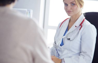 Bir doktor konuşuyor ve bir hastayı muayene ediyor.