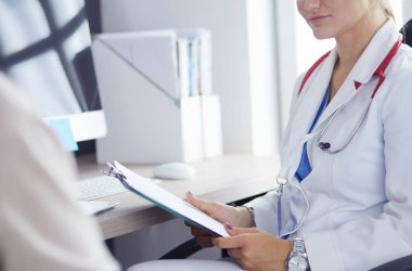 Bir doktor konuşuyor ve bir hastayı muayene ediyor.