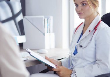 Bir doktor konuşuyor ve bir hastayı muayene ediyor.