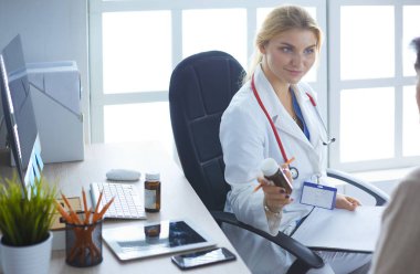 Bir doktor konuşuyor ve bir hastayı muayene ediyor.