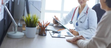 Bir doktor konuşuyor ve bir hastayı muayene ediyor.