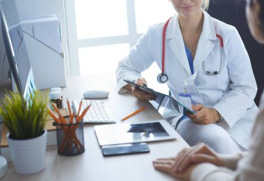 Bir doktor konuşuyor ve bir hastayı muayene ediyor.