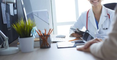 Bir doktor konuşuyor ve bir hastayı muayene ediyor.