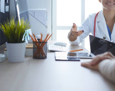 Bir doktor konuşuyor ve bir hastayı muayene ediyor.