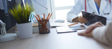 Bir doktor konuşuyor ve bir hastayı muayene ediyor.