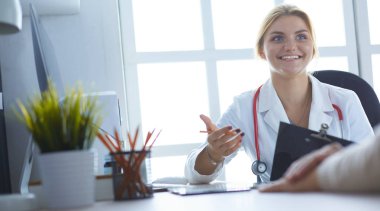 Bir doktor konuşuyor ve bir hastayı muayene ediyor.