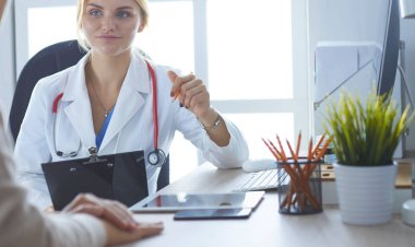 Kadın doktor hastaya danışmanlık yaparken başvuru formu tutuyor